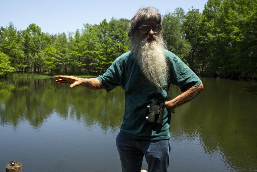 Hugh Brown at a pond on his property ringed with cypress trees he planted 30 years ago, pictured on May 7, 2025.